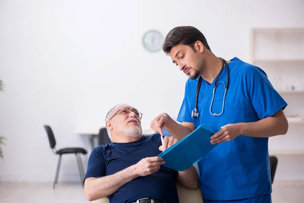 Vecchio visitando giovane medico maschio — Foto Stock