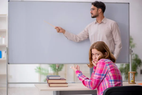 Ung manlig lärare och rödhårig flicka i klassrummet — Stockfoto