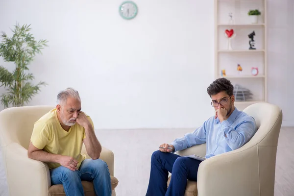 Oude man op bezoek bij jonge mannelijke psychotherapeut — Stockfoto