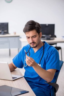 Klinikte çalışan genç erkek doktor.