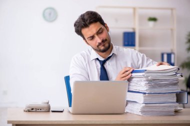 Ofisteki aşırı işten memnun olmayan genç bir erkek işçi.