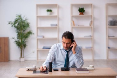 Masasında çalışan genç bir erkek çağrı merkezi operatörü.