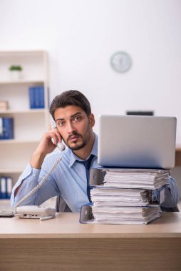 Genç bir erkek çalışan ve ofiste çok fazla iş var.