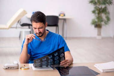 Genç erkek doktor radyoloji uzmanı klinikte oturuyor.