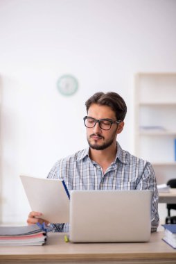 Genç erkek çalışan ofiste oturuyor.