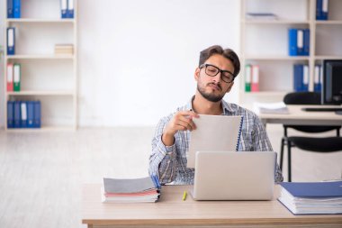 Genç erkek çalışan ofiste oturuyor.