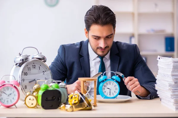 Joven empleado de negocios comiendo despertador-reloj —  Fotos de Stock