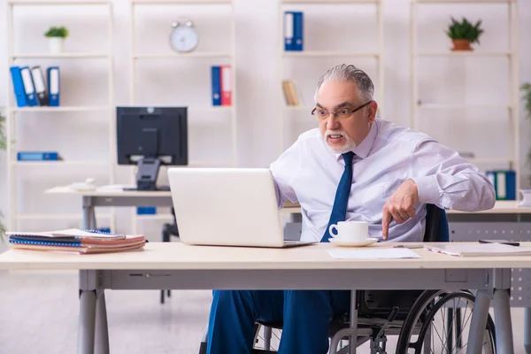 Stary mężczyzna pracownik na wózku inwalidzkim siedzi w biurze — Zdjęcie stockowe