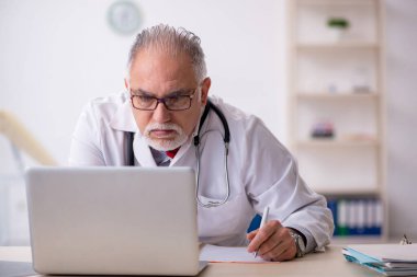 Klinikte çalışan yaşlı erkek doktor.