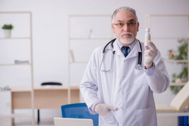 Klinikte çalışan yaşlı erkek doktor.