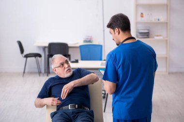 Yaşlı adam genç erkek doktoru ziyaret ediyor.