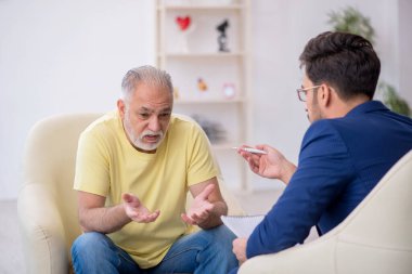 Yaşlı adam genç erkek psikoterapisti ziyaret ediyor.