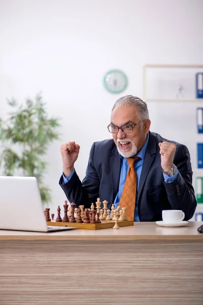 Viejo empresario jugando ajedrez en el lugar de trabajo — Foto de Stock