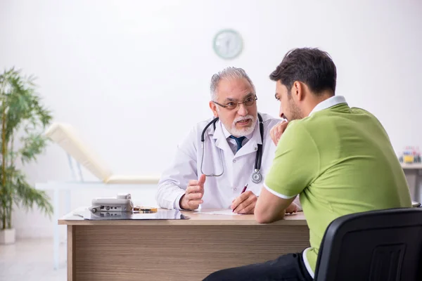 Jovem visitando velho médico masculino — Fotografia de Stock