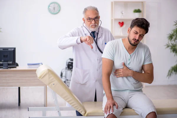 Junge männliche Patientin besucht alten männlichen Arzt — Stockfoto