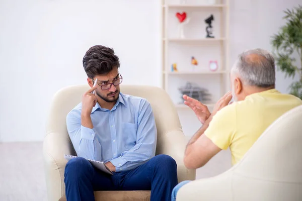 Oude man op bezoek bij jonge mannelijke psychotherapeut — Stockfoto