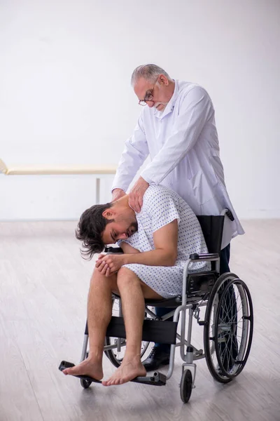 Old male doctor psychiatrist examining young disabled patient