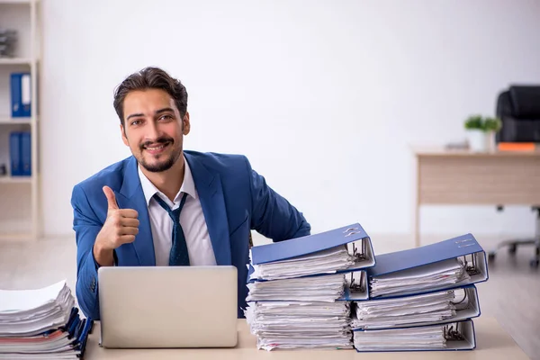 Young male employee and too much work in the office — Stock Photo, Image