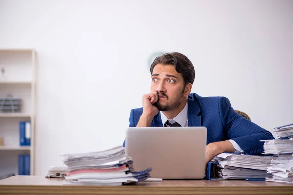 Ung manlig anställd och för mycket arbete på kontoret — Stockfoto