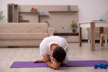 Genç adam evde spor yapıyor.