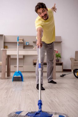 Genç adam evde ev işi yapıyor.