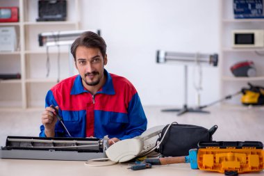 Klimayı tamir eden genç bir erkek tamirci