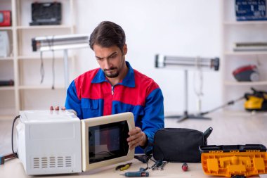 Atölyede fırını tamir eden genç bir erkek tamirci.