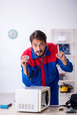 Atölyede fırını tamir eden genç bir erkek tamirci.