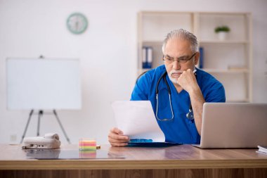 Klinikte çalışan yaşlı erkek doktor.