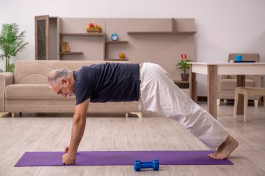 Yaşlı adam evde spor yapıyor.