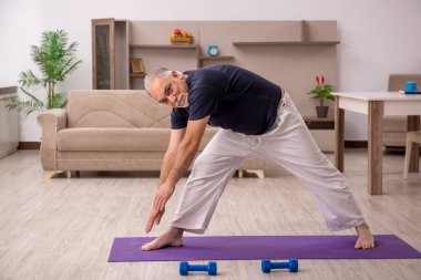 Yaşlı adam evde spor yapıyor.