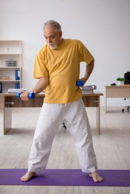 Ofiste spor egzersizleri yapan eski bir işadamı.