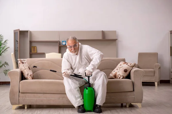 Velho empreiteiro masculino fazendo controle de pragas em casa — Fotografia de Stock