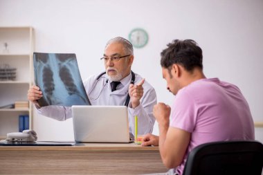 Genç erkek hasta yaşlı erkek doktor radyolojisti ziyaret ediyor.