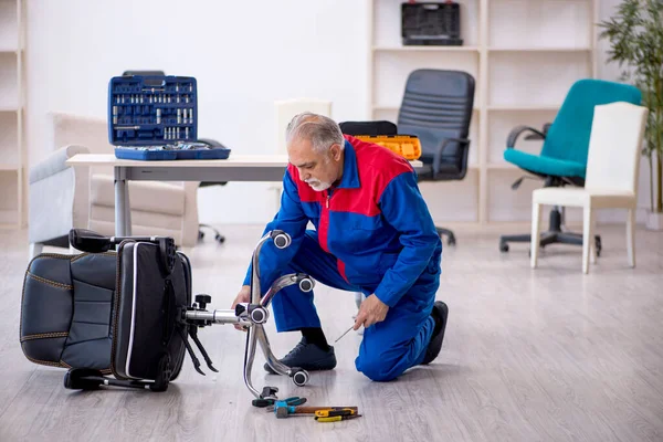 Homem velho reparador reparando cadeira de escritório — Fotografia de Stock