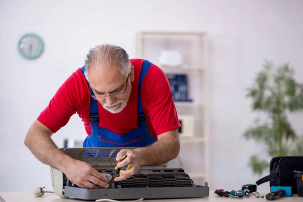 Alter Reparateur repariert Klimaanlage in der Werkstatt — Stockfoto