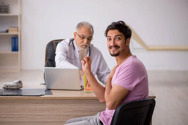 Junge männliche Patientin besucht alten männlichen Arzt — Stockfoto