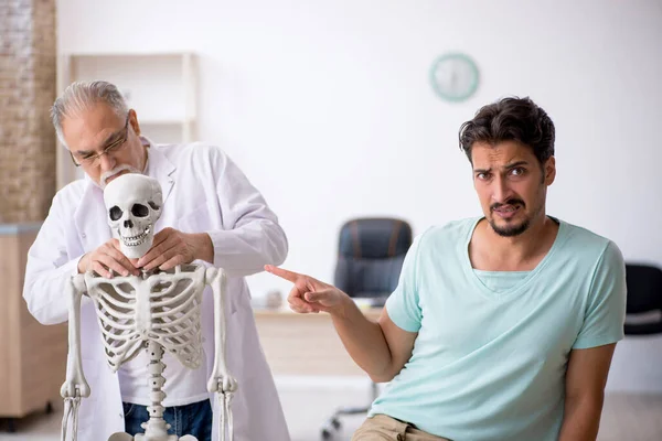 Joven paciente masculino visitando viejo médico masculino —  Fotos de Stock