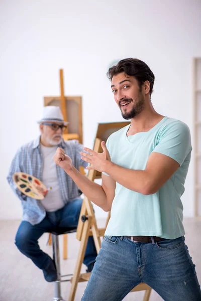 Старый художник и молодой мужчина-модель в студии — стоковое фото