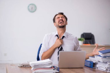 Genç bir erkek çalışan ve ofiste çok fazla iş var.