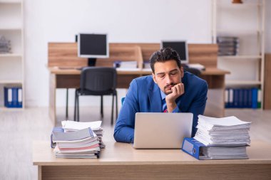 Genç erkek çalışan işyerinde aşırı çalışmaktan memnun değil.