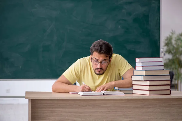 Jonge mannelijke student bereidt zich voor op examens in de klas — Stockfoto