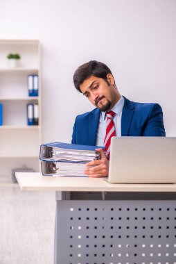 Ofisteki aşırı işten memnun olmayan genç bir erkek işçi.