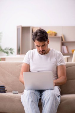 Genç erkek çalışan salgın sırasında evden çalışıyor.