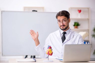 Sınıfta oturan genç erkek kardiyolog.