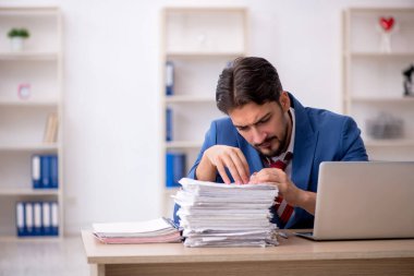 Genç bir erkek çalışan ve ofiste çok fazla iş var.