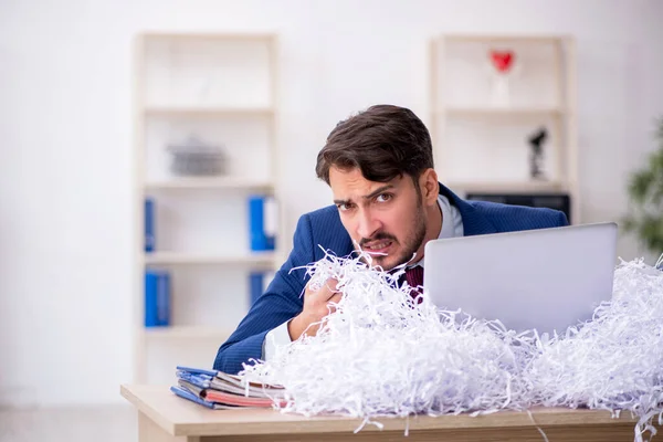 Genç bir erkek çalışan ve ofiste bir sürü kesik kağıt var. — Stok fotoğraf