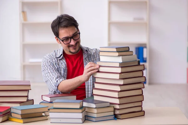 Jovem estudante do sexo masculino e muitos livros em sala de aula — Fotografia de Stock