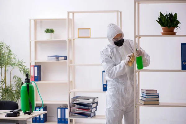 Contratista masculino joven desinfectando oficina durante pandemia — Foto de Stock