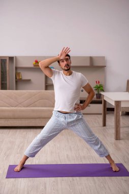 Genç adam evde spor yapıyor.